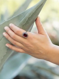 Faceted Garnet Ring with Rope Edge worn by model holding onto a cactus leaf