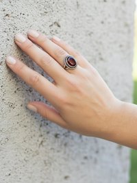 Faceted Garnet Ring with Rope Edge worn by model leaning against a stone wall