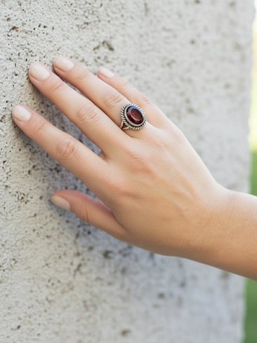 Faceted Garnet Ring with Rope Edge worn by model leaning against a stone wall